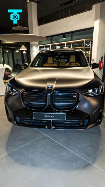 BMW X3 noire mate de face dans un showroom