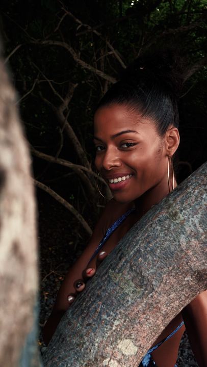 Portrait en extérieur d'une femme souriante appuyée contre un arbre