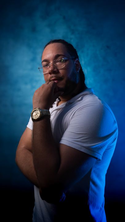 Portrait professionnel en studio d'un homme, main au menton, sur fond bleu
