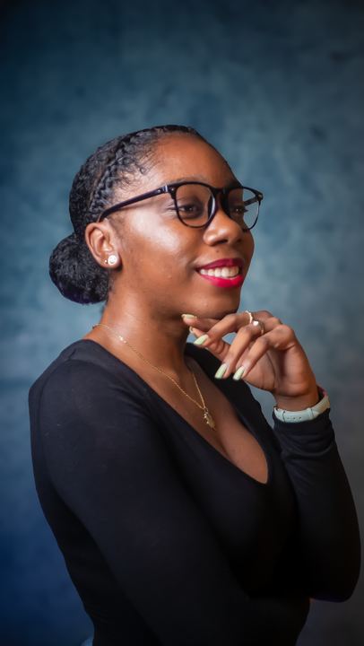 Portrait en studio d'une femme souriante à lunettes, main sous le menton