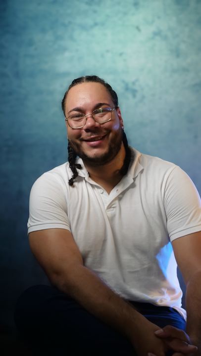 Portrait en studio d'un homme souriant en polo blanc, sur fond bleu